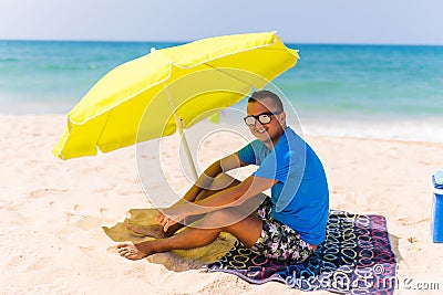 Lazing man in sun under solar umbrella on towel enjoy the lazy time on the beach Stock Photo