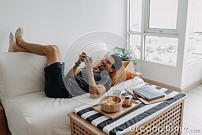 Lazy happy man playing mobile game while he should have work from home. Stock Photo