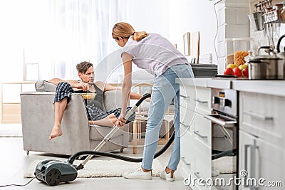 Lazy husband watching TV and his wife cleaning Stock Photo