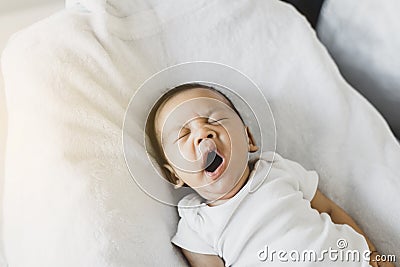 Lazy newborn baby yawning before sleep on a comfortable bed at home Stock Photo