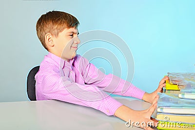 Lazy and stupid teenager does not want to learn and pushes textbooks from himself, sitting at his desk Stock Photo