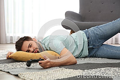 Lazy man playing video game while lying on floor at home Stock Photo