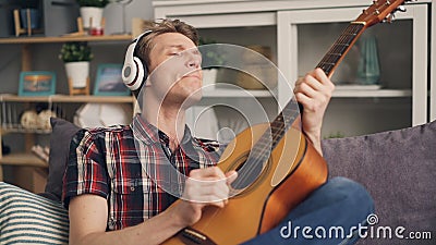 Le type émotif est chantant et jouant la guitare tout en écoutant la musique dans des écouteurs riant alors ayant l'amusement gen clips vidéos Le type émotif est chantant et jouant la guitare tout en écoutant la musique dans des écouteurs riant alors ayant l'amusement gen clips vidéos