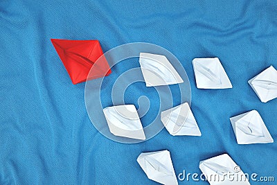 Leadership and initiative concept. Red paper boat leading a group of white paper boat. Stock Photo