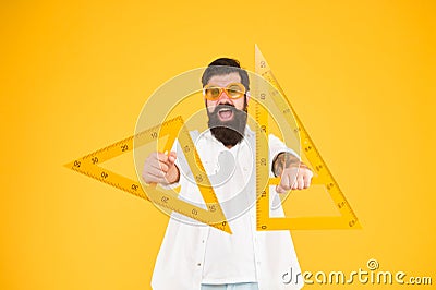 Leading engineer of the project. Smart engineer holding triangles on yellow background. Teaching engineer smiling with Stock Photo
