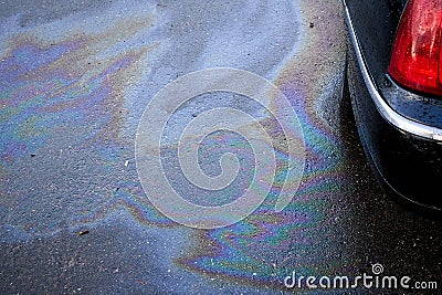 Leakage of oil or gasoline from the car on the asphalt in the parking lot. Stock Photo