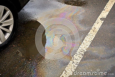 Leakage of oil or gasoline from the car on the asphalt in the parking lot. Stock Photo