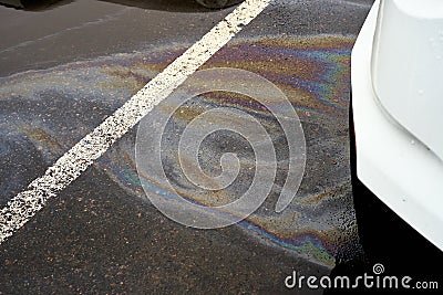 Leakage of oil or gasoline from the car on the asphalt in the parking lot. Stock Photo