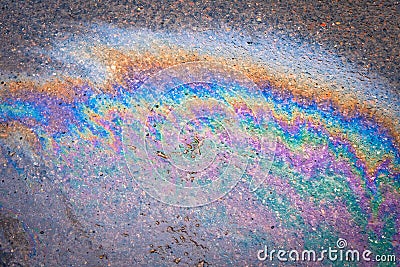 Leakage of oil or gasoline from a car onto a wet asphalt road during snowmelt Stock Photo