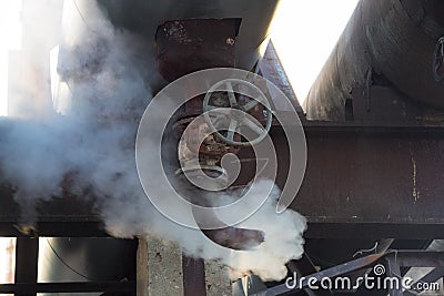 Leakage of steam in heat pipeline. Steam outgoing from the rusty tube with valve Stock Photo
