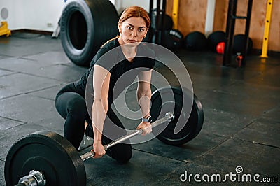 Leaning on the barbell. On the floor. Beautiful strong woman is in the gym Stock Photo