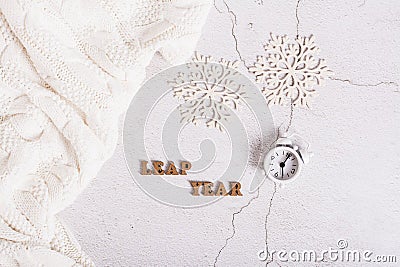 Leap year concept, calendar, alarm clock, sweater and snowflakes on a light top view Stock Photo