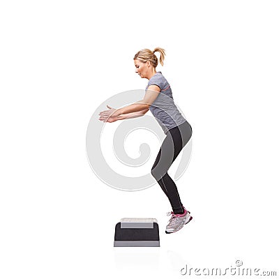 Leaping up in pursuit of fitness. A smiling young woman doing aerobics on an aerobic step against a white background. Stock Photo