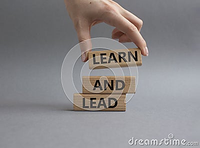 Learn and lead symbol. Concept words Learn and lead on wooden blocks. Beautiful grey background. Businessman hand. Business and Stock Photo