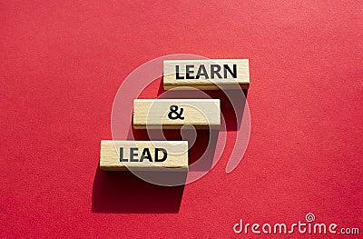 Learn and lead symbol. Concept words Learn and lead on wooden blocks. Beautiful red background. Business and Learn and lead Stock Photo