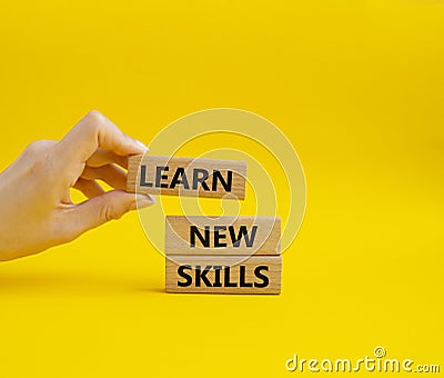 Learn new skills symbol. Concept words Learn new skills on wooden blocks. Beautiful yellow background. Businessman hand. Stock Photo