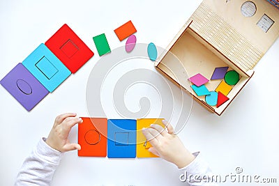 Learning colors and shapes. Children\'s wooden toy. The child collects a sorter. Educational logic toys for kid\'s. Kindergarten Stock Photo