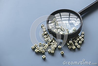 Learning and education concept. Finding keywords. Language learning. Magnifying glass on a bunch of alphabet beads Stock Photo