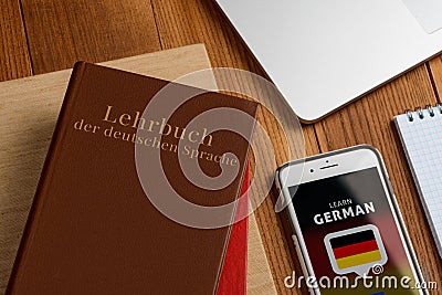 Learning German book and app. Using phone to do exercises Stock Photo