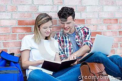 Learning german students with book and laptop Stock Photo