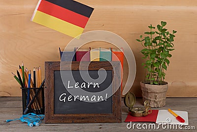 Learning languages concept - blackboard with text "Learn German", flag of the Germany, books, chancellery Stock Photo