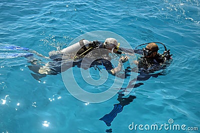 Learning process of scuba diving. Experienced instructor teaches beginner to dive into sea using scuba gear. Editorial Stock Photo