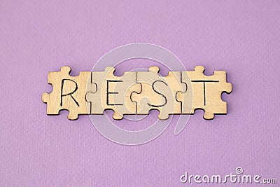 Learning Rest. The hand lettering on the wooden puzzles is on a purple background Stock Photo