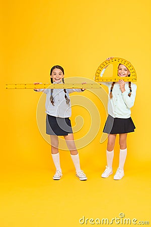 Learning school geometry. School children with measuring instruments on yellow background. Cute pupils holding Stock Photo