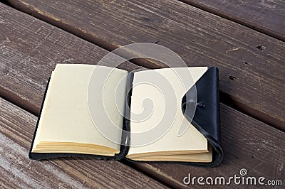 Leather bound black journal outdoors on table with blank pages Stock Photo