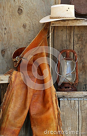 Leather chaps, cowboy hats, lantern on shelf Stock Photo