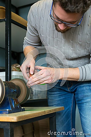 Leather craftsman sharpens knife for cutting leather on sander. Handmade concept. Concept of small business to create leather Stock Photo