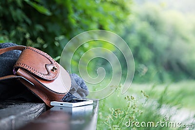 Leather handbag, smartphone and jacket on a park bench, nobody Stock Photo