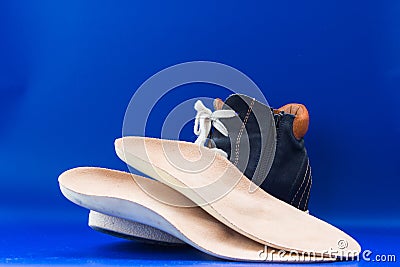 Leather orthopedic insoles with boot. Blue background. Stock Photo