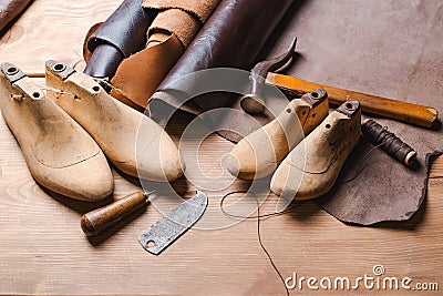 Leather in rolls, cobbler tools and shoe lasts in workshop. Leather craft tools. Stock Photo