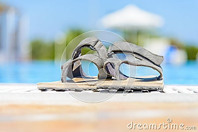 Leather sandals are on the edge of the swimming pool Stock Photo