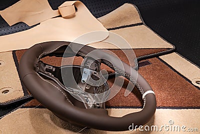 Leather steering wheel brown color in the process of stitching with a bright contrast seam and white central point on the top in Stock Photo