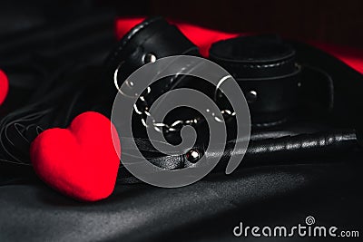 Leather whip and handcuffs for BDSM sex with red hearts as a symbol of Valentine`s day Stock Photo