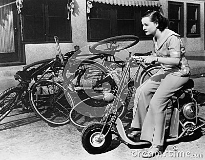 Leaving bicycles in the dust, a young woman fancies a miniature motorbike Stock Photo