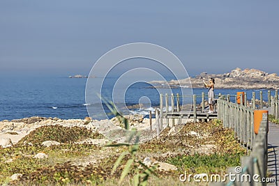 Leca da Palmeira/Porto/Portugal - 10 04 2018: View of woman taking pictures on pedestrian wooden walkway, beach and sea as Editorial Stock Photo