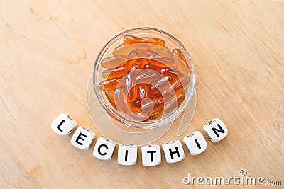 Lecithin gel pills in a round glass bowl and with the word Lecetin from the letters of cubes on a light wooden background. Soy Stock Photo