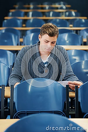 Lecture hall, college and man with thinking, student and knowledge with exam and education. Person, writing and guy in Stock Photo