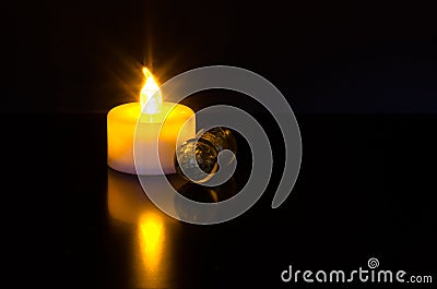 Led candle light with sparkly reflection and green marble balls on black background Stock Photo