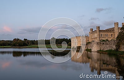 Leeds Castle in Kent UK, reflected in the surrounding moat, photographed in late afternoon on a clear crisp autumn day. Stock Photo