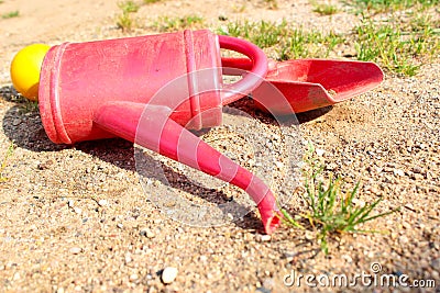 Left children toys on the sand. Red watering can, shovel and yellow ball. Stock Photo