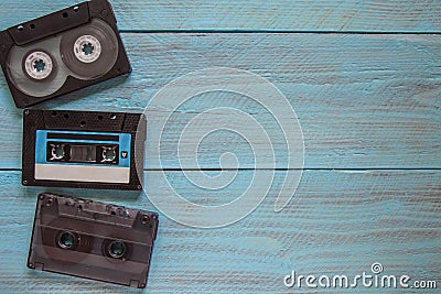 In the left corner of the frame, on a blue wooden background, there are three audio cassettes. On the right, there is an empty Stock Photo