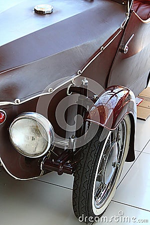 Left headlight and front wheel with visible part of the Axle of veteran Czechoslovak tricycle automobile Velorex 350 Editorial Stock Photo