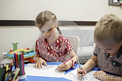 Lefty girl and righty boy writing at same desk and nudge each other with elbows, left-hander day Stock Photo