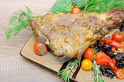 Leg of lamb with vegetables, greens and prunes on a plate on a w Stock Photo