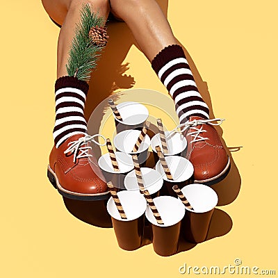 Leg in vintage striped socks and shoes in stylish isometric sweet cups space. Minimal still life food art. Chocolate lover. Stock Photo