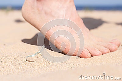 Leg walks on the beach and runs the risk of injury, stepping on a shard of broken glass of a bottle, which is lying on Stock Photo